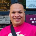 A man in a pink shirt standing outside.