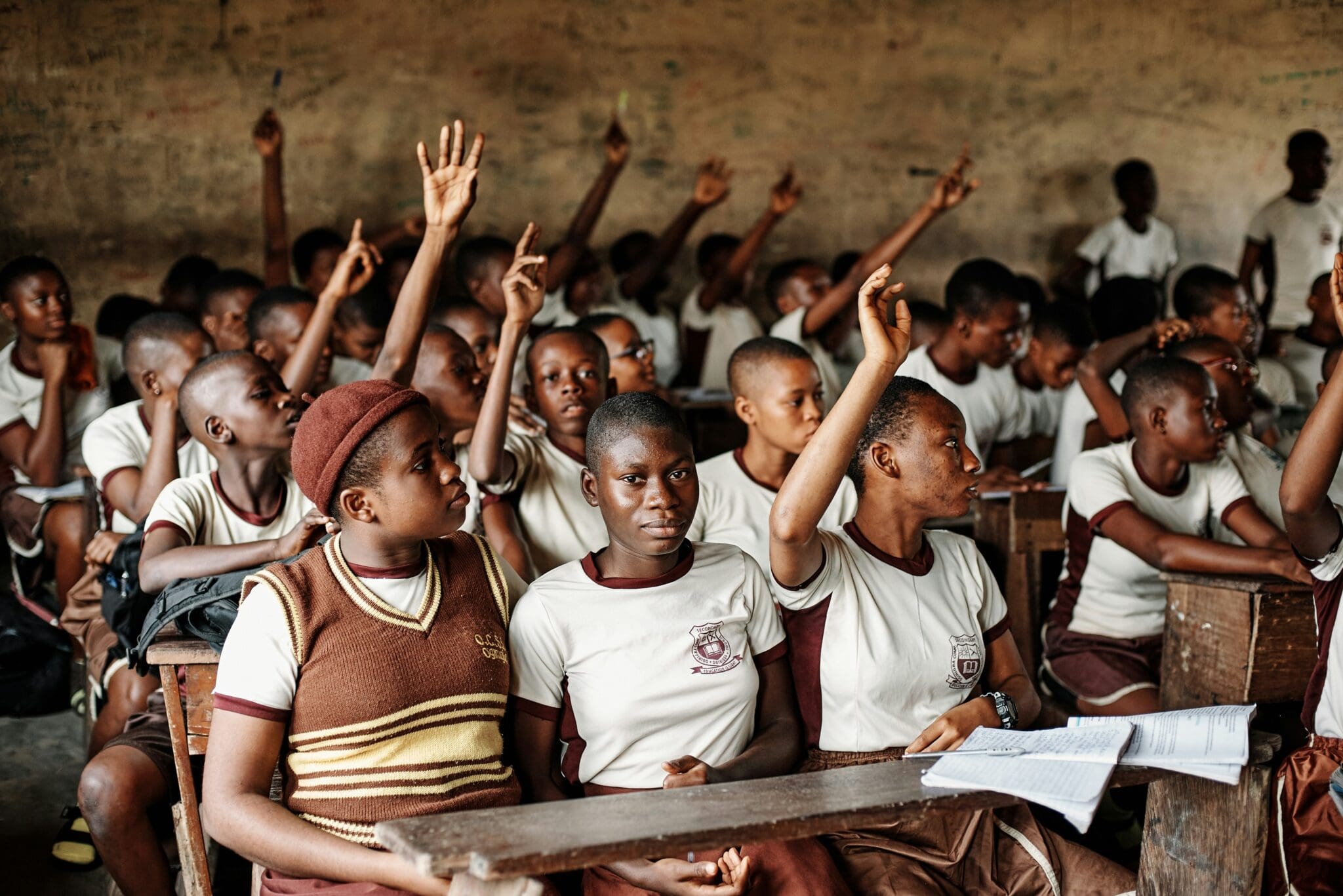 A group of people sitting in a room with their hands raised.