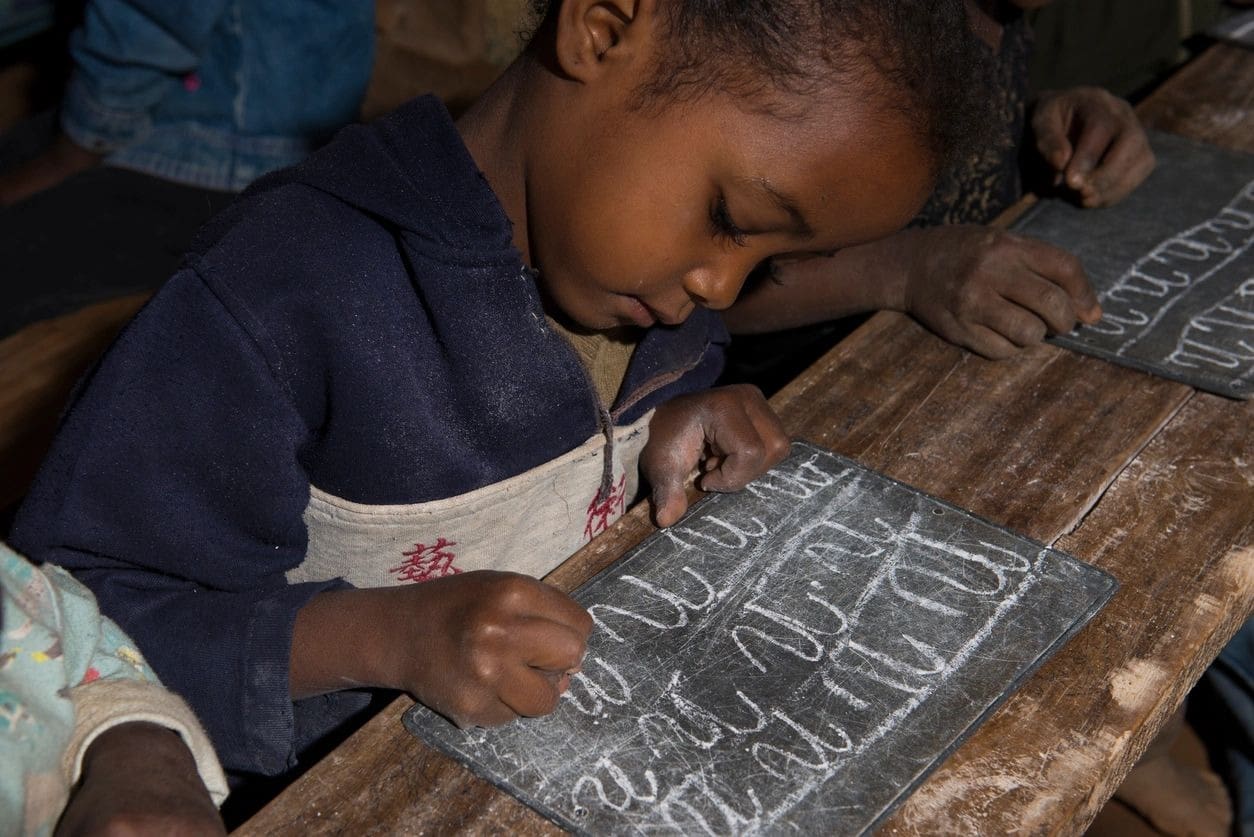 A child is sitting at the table and writing on paper.