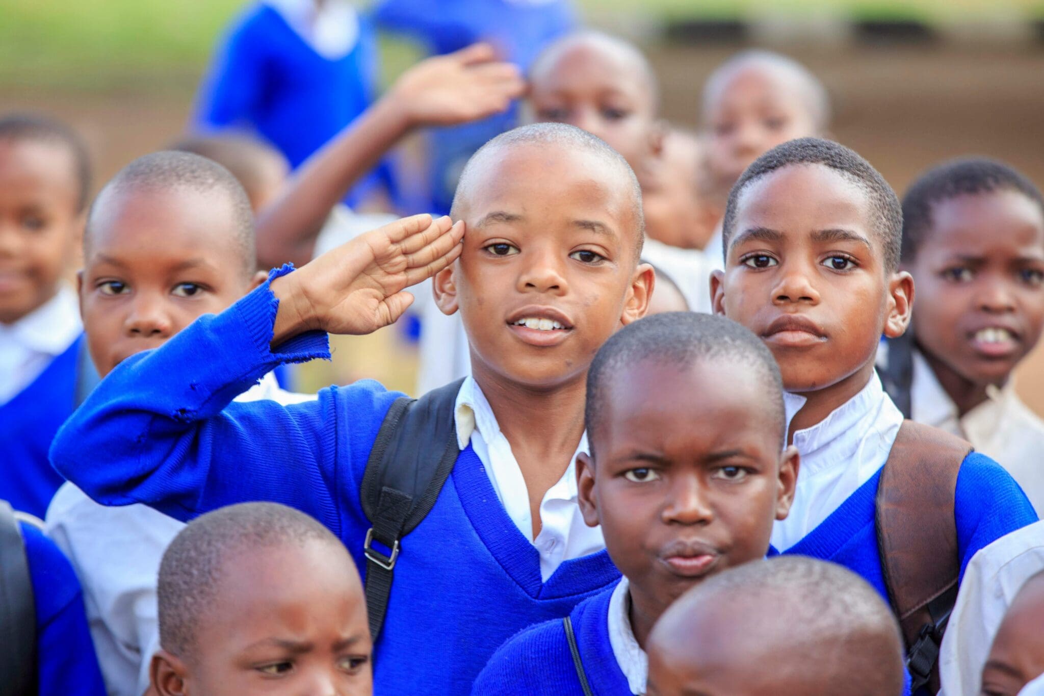 A group of young boys in school uniforms saluting.