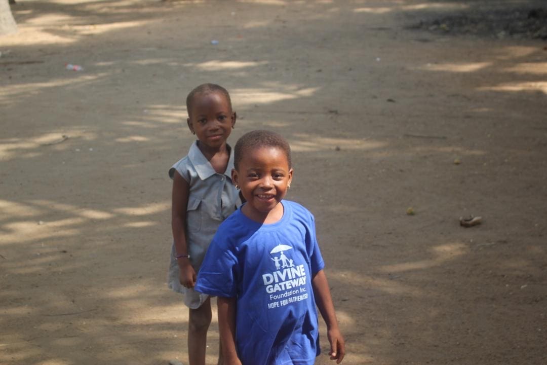 Two children standing in the dirt together.