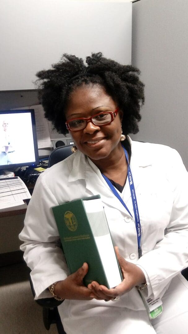 A woman holding a passport in front of a computer.