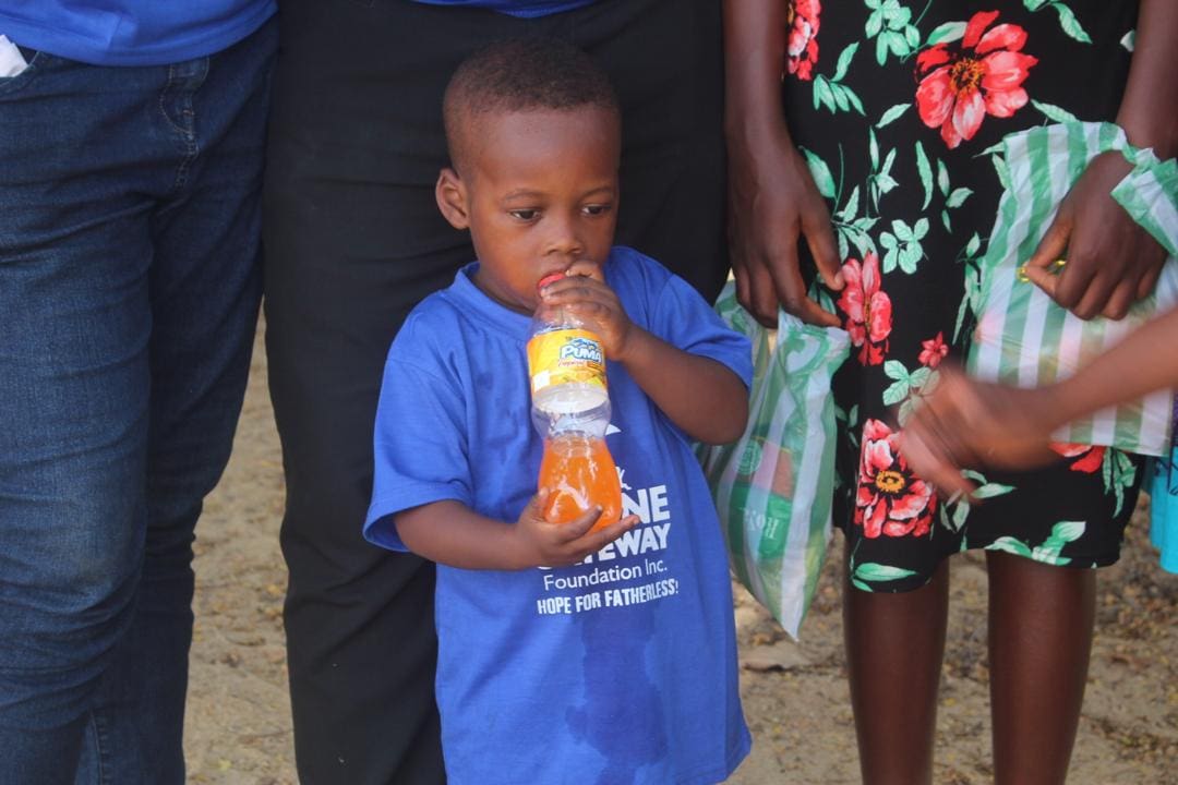 A young boy holding an orange in his hand.