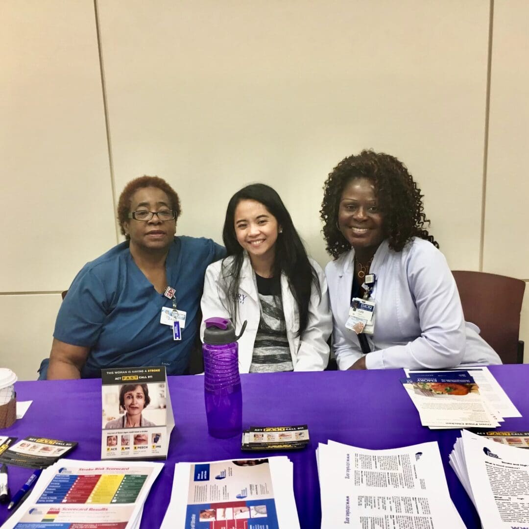 Three women sitting at a table with papers on it.