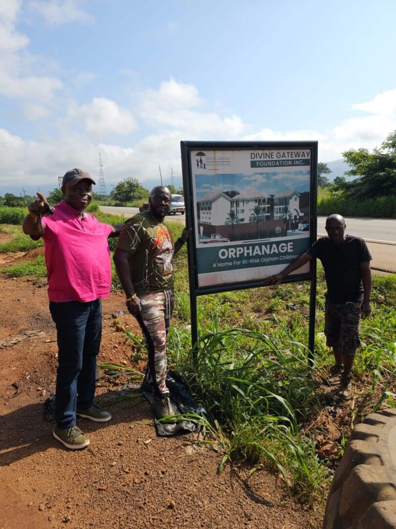 Three people standing next to a sign on the side of a road.