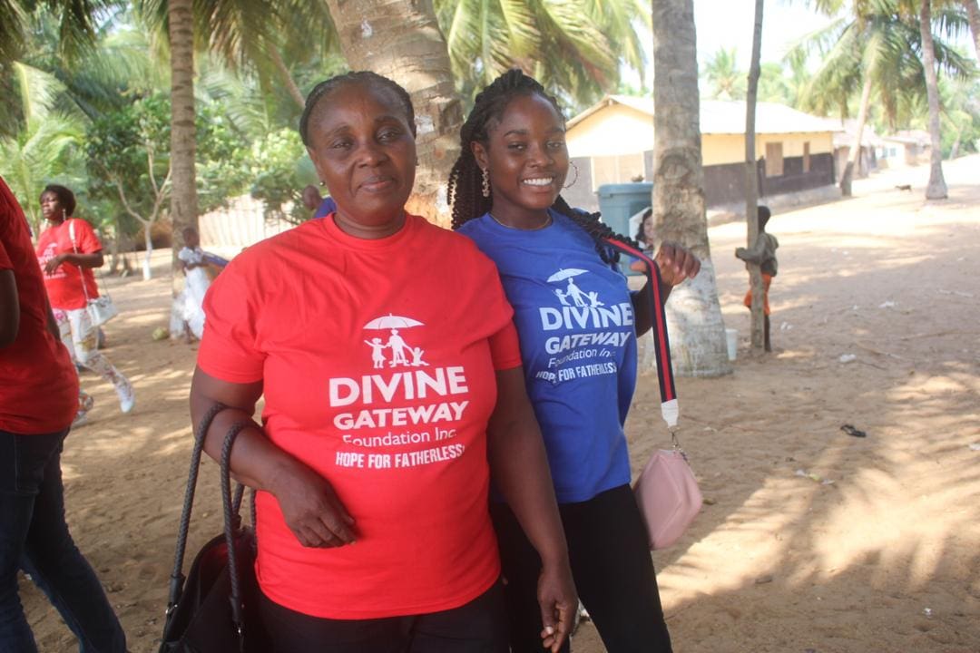 Two women standing next to each other in front of a tree.