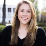 A woman with long hair and wearing black is smiling.