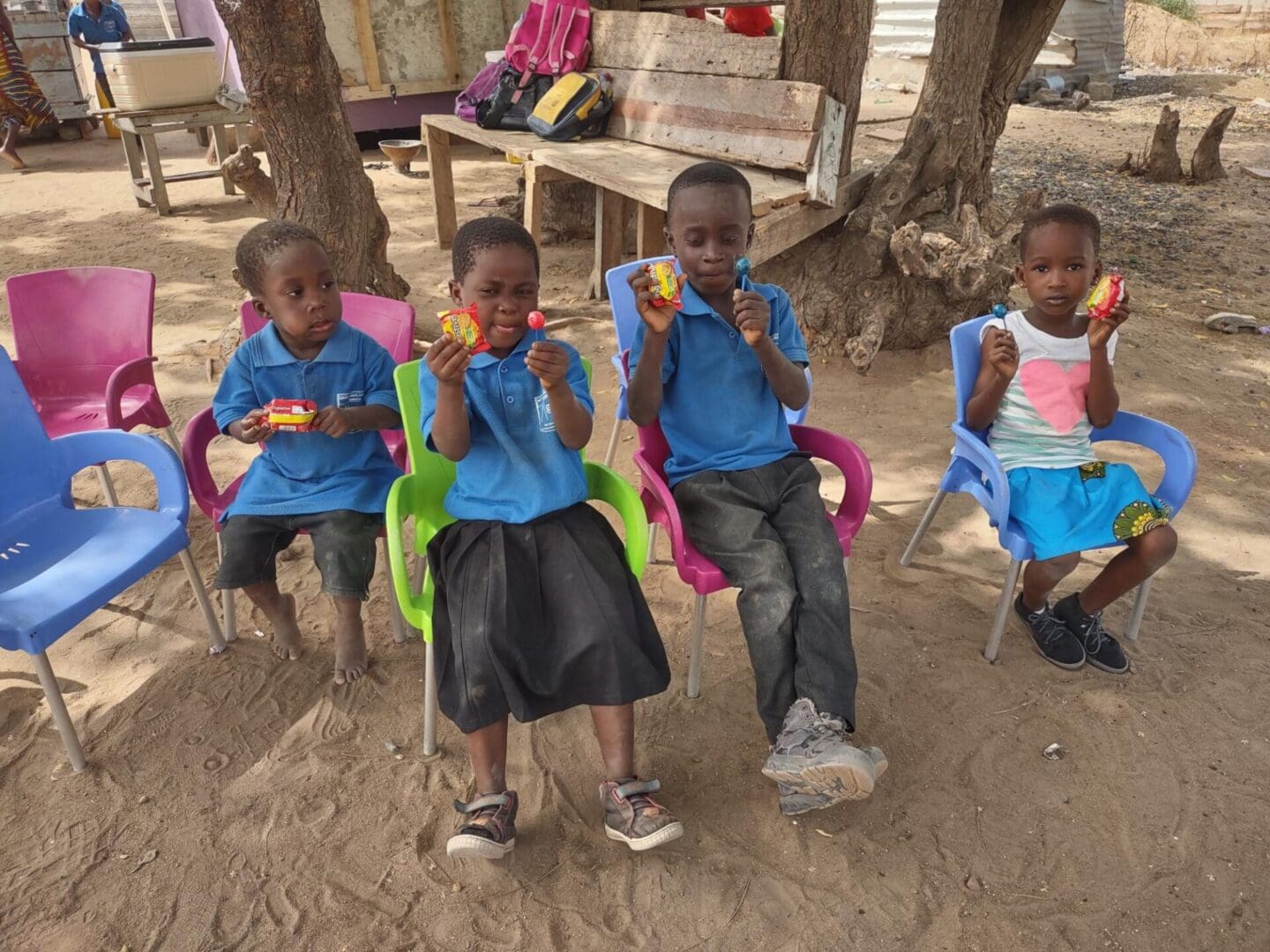 A group of children sitting in lawn chairs eating.