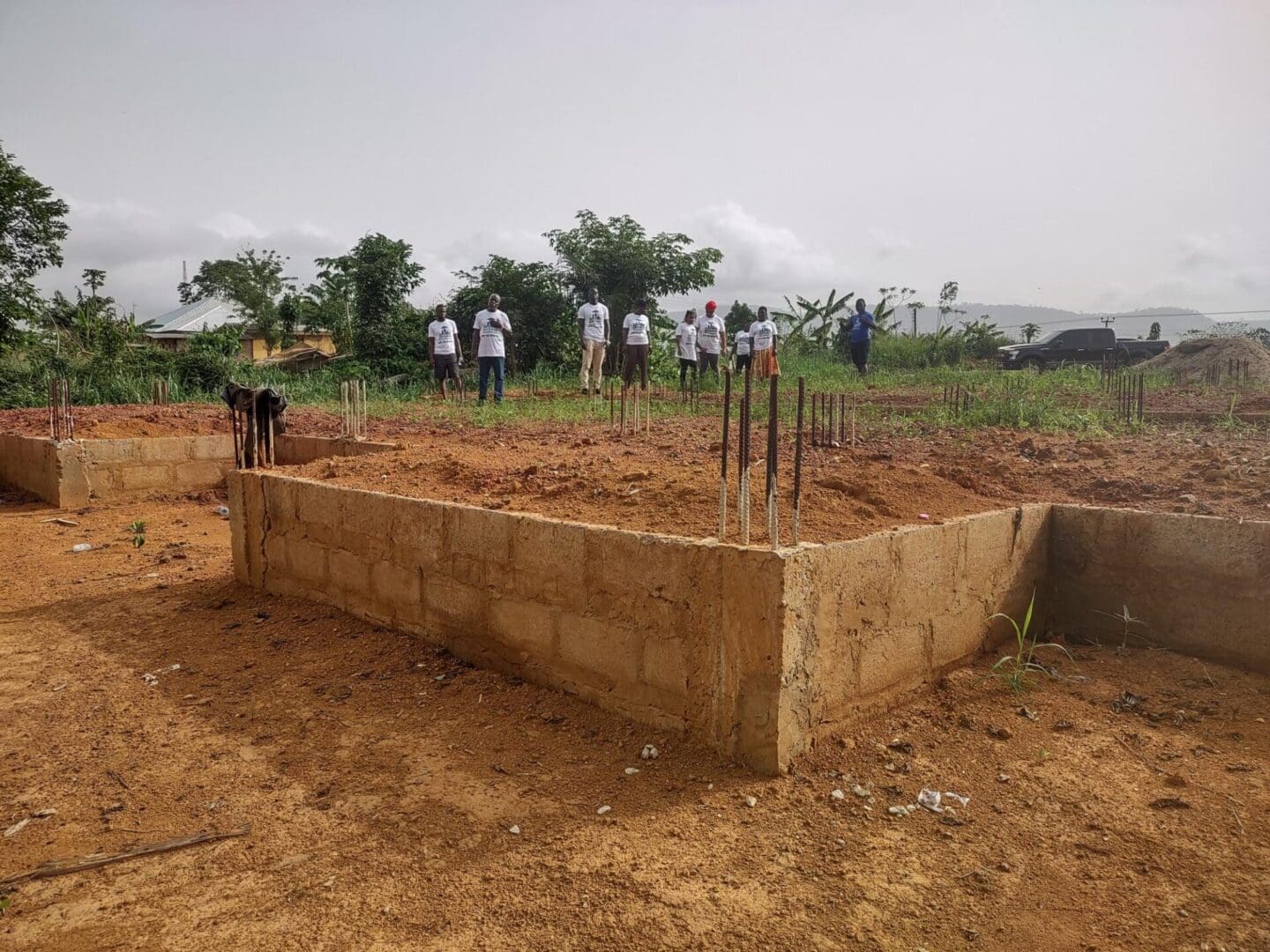 A group of people standing around a dirt field.