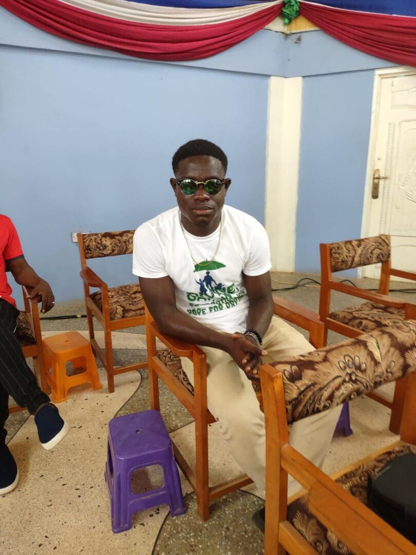 A man sitting on top of a wooden chair.