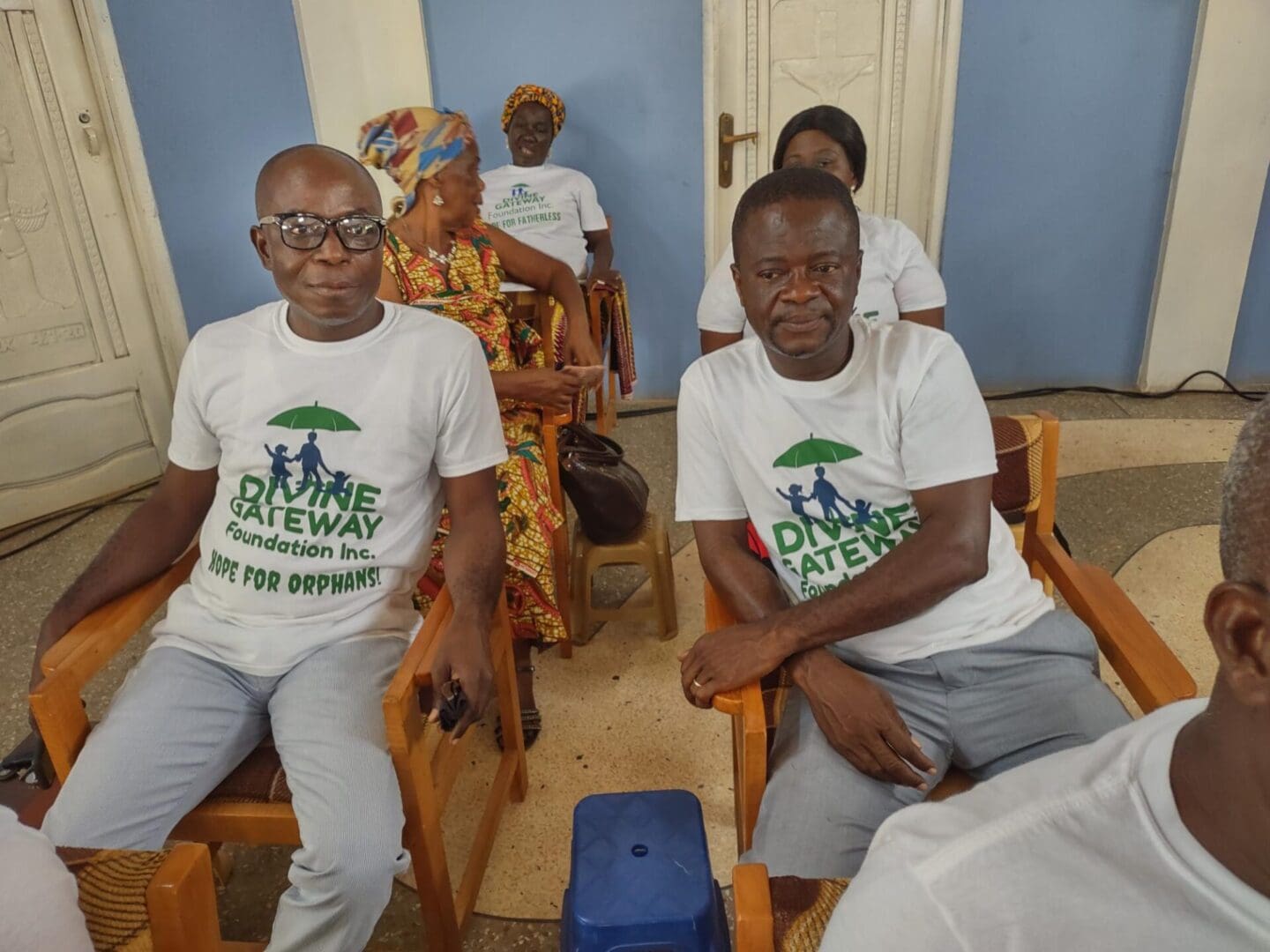 A group of people sitting in chairs with one man wearing glasses.