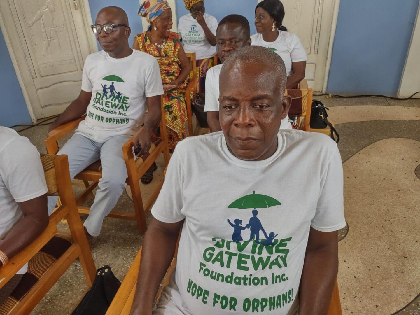 A group of people sitting in chairs wearing white shirts.