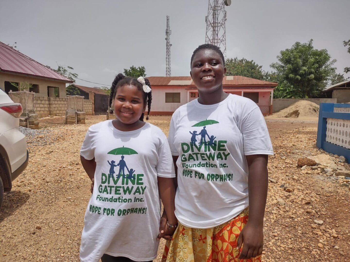 Two people standing next to each other on a dirt field.