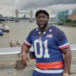 A man in blue and white shirt standing next to water.