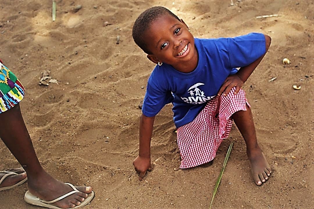 A young boy is smiling while playing in the sand.