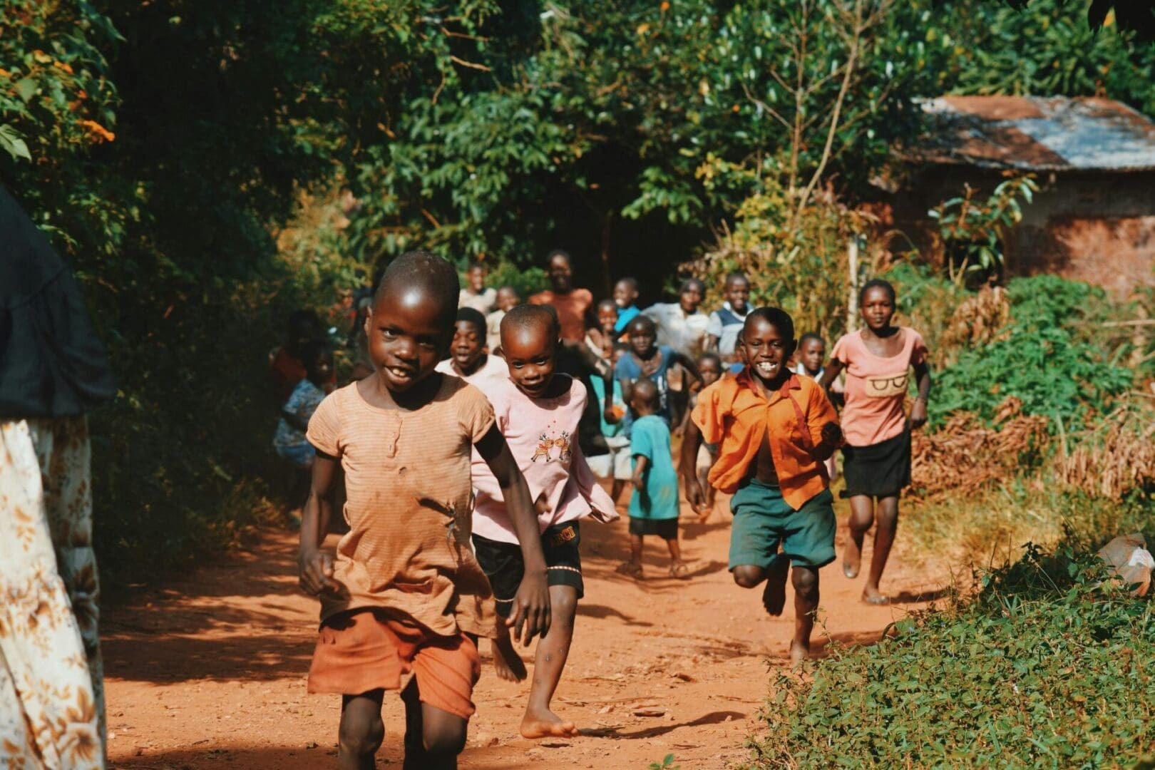 A group of children are running down the dirt road.