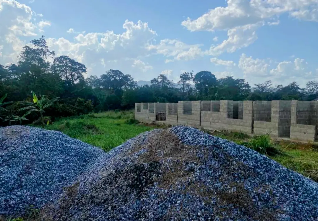 A pile of blue and black rocks in front of a fence.